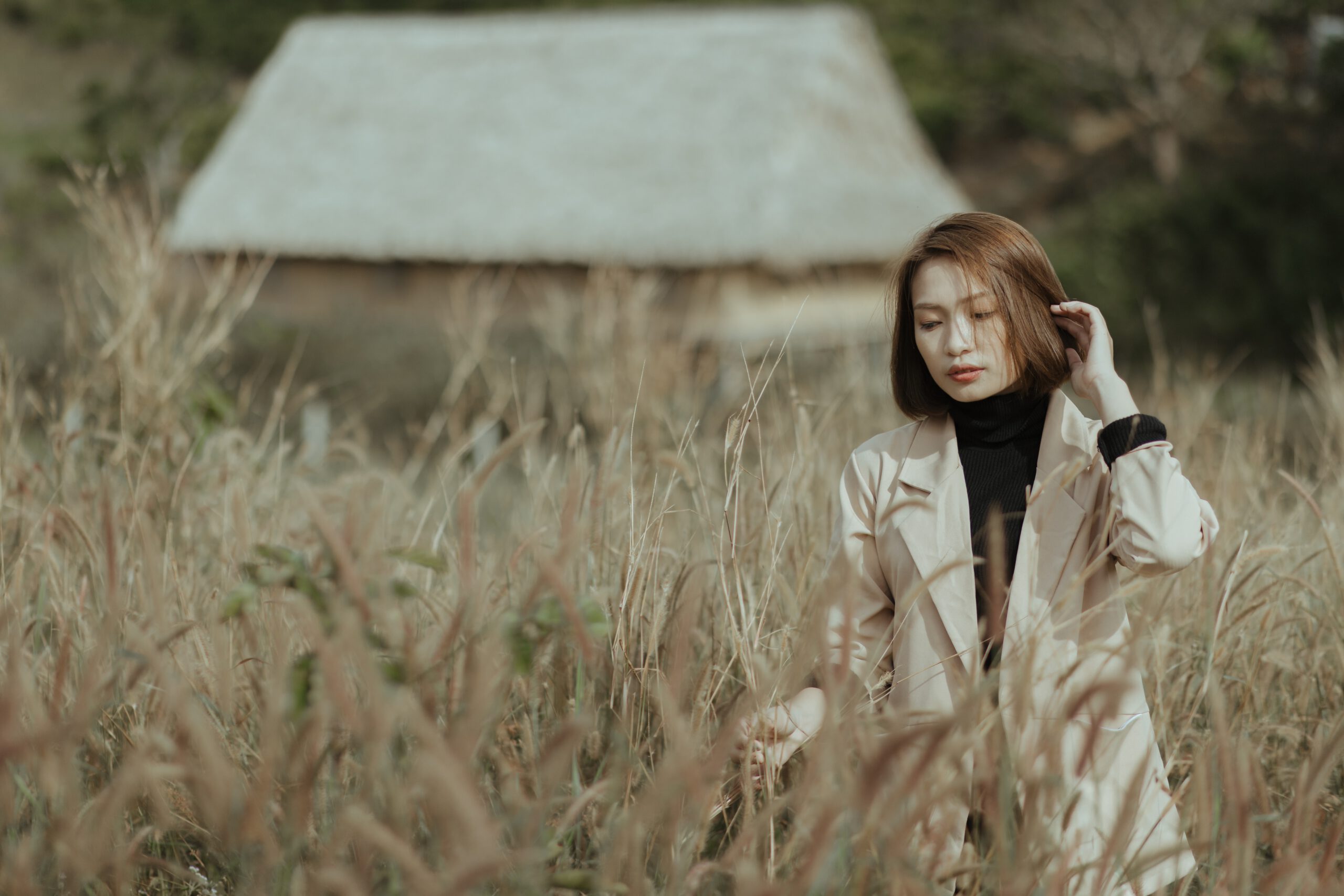 Młoda kobieta w płaszczu wśród wysokich ozdobnych traw