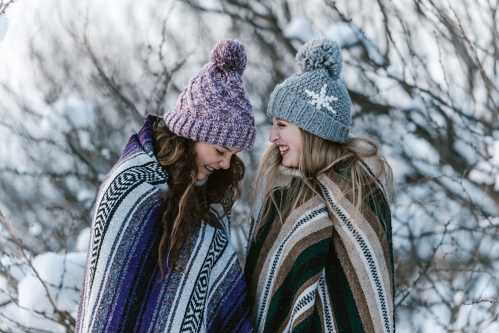 Dwie siostry na spacerze w parku podczas zimowego dnia, mają na sobie koce które podarowały sobie jako prezenty świąteczne